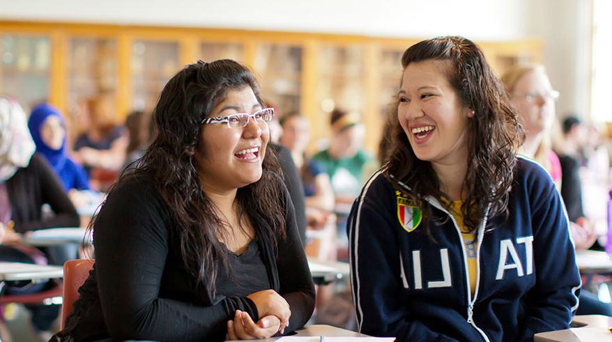 Two students laughing in a classroom.